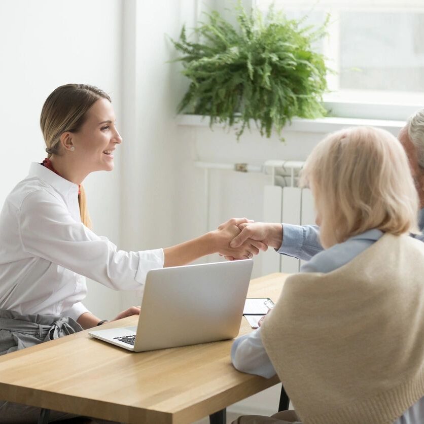 A woman shaking hands with another person at a table.